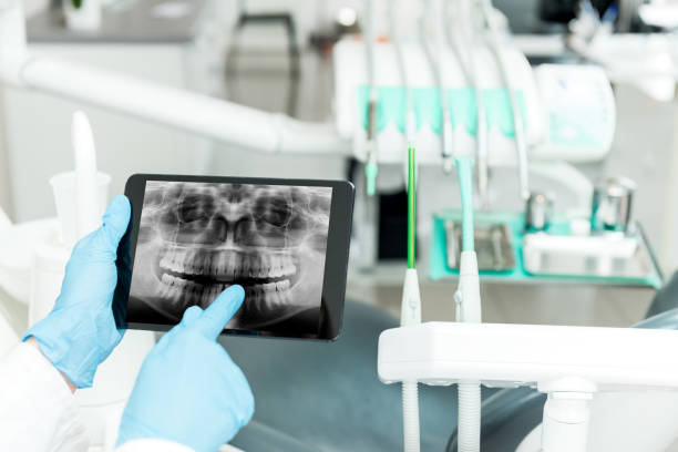 Horizontal close-up image of dentist holding tablet